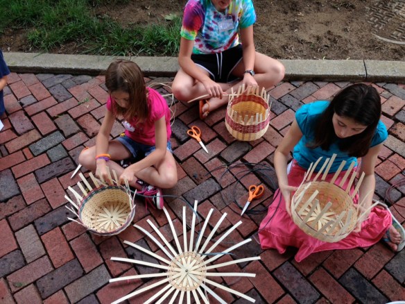 kids on sidewalk weaving baskets