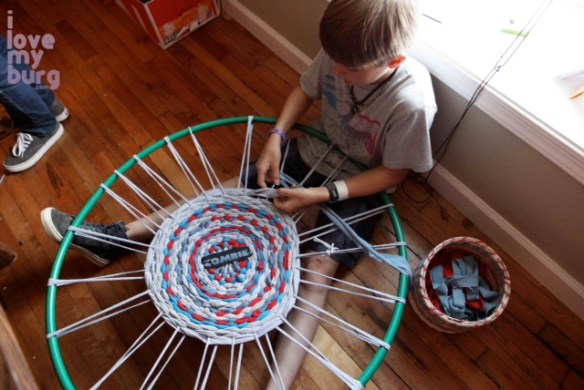 boy weaving hula hoop rug