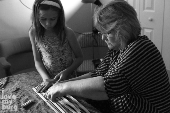 girl and grandmother weaving basket